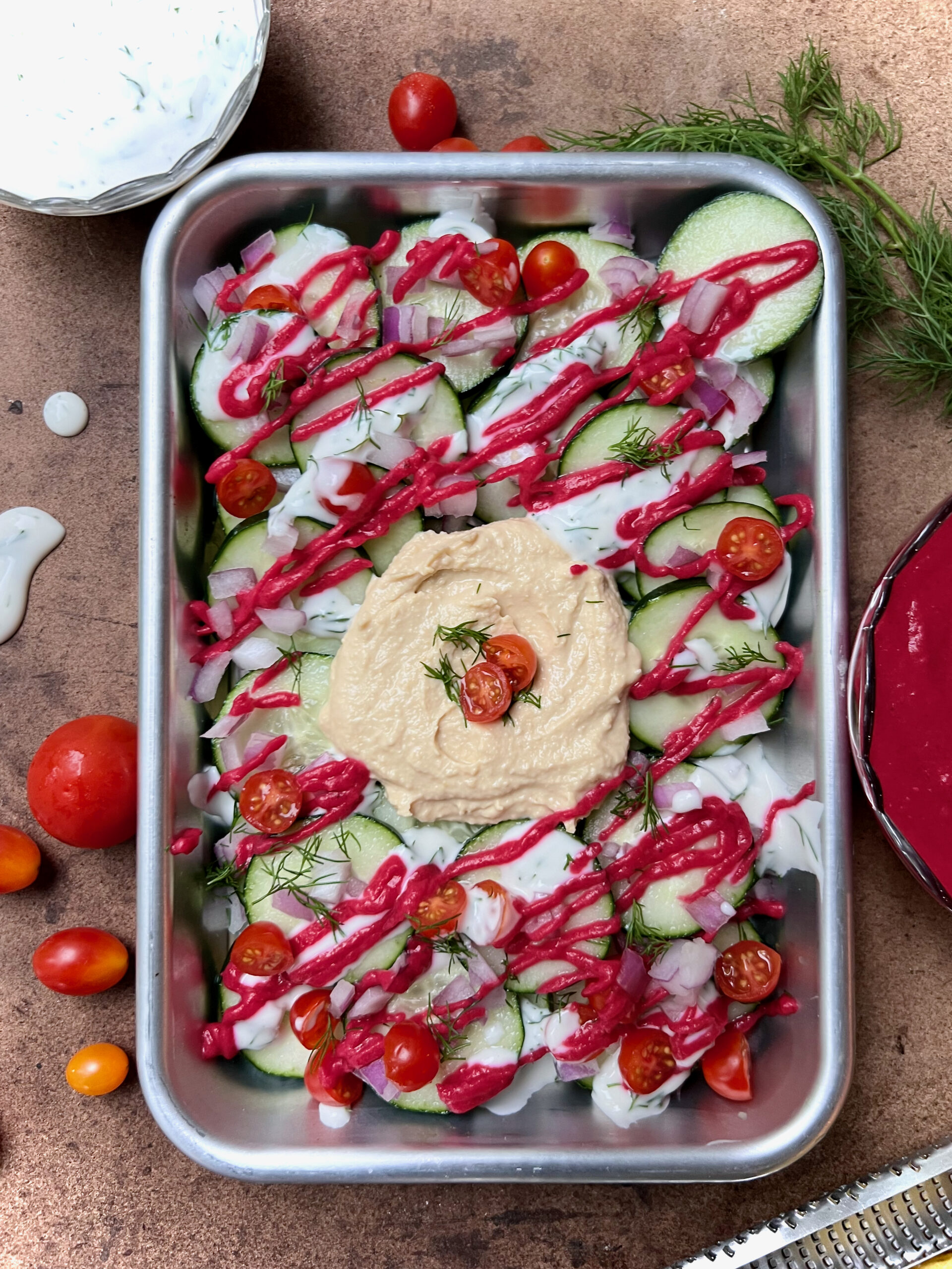 tray of greek nachos with hummus, beet sauce, and tzaziki sauce